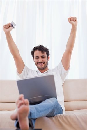 simsearch:400-04410667,k - Portrait of a cheerful man shopping online in his living room Stock Photo - Budget Royalty-Free & Subscription, Code: 400-05741537