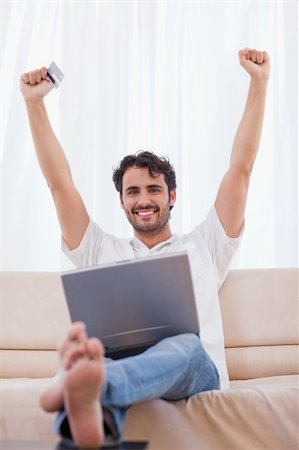 simsearch:400-04410667,k - Portrait of a cheerful man buying online in his living room Stock Photo - Budget Royalty-Free & Subscription, Code: 400-05741538