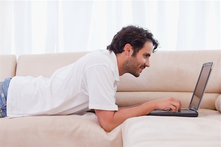 simsearch:400-04412244,k - Handsome man using a laptop in his living room Stock Photo - Budget Royalty-Free & Subscription, Code: 400-05741530