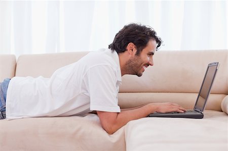 simsearch:400-04412244,k - Handsome man using a notebook in his living room Stock Photo - Budget Royalty-Free & Subscription, Code: 400-05741531