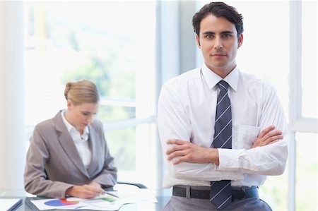 Businessman posing while his colleague is working in a meeting room Stock Photo - Budget Royalty-Free & Subscription, Code: 400-05741998