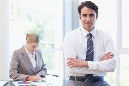 simsearch:400-05746962,k - Young businessman posing while his colleague is working in a meeting room Stock Photo - Budget Royalty-Free & Subscription, Code: 400-05741999