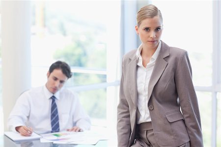 simsearch:400-05746962,k - Businesswoman posing while her colleague is working in a meeting room Stock Photo - Budget Royalty-Free & Subscription, Code: 400-05742000