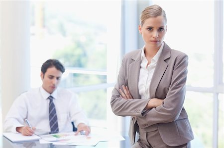 simsearch:400-05746962,k - Serious businesswoman posing while her colleague is working in a meeting room Stock Photo - Budget Royalty-Free & Subscription, Code: 400-05742001