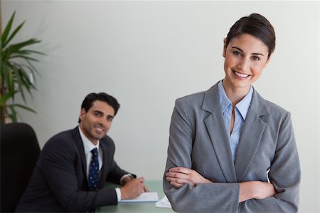 simsearch:400-05746962,k - Happy businesswoman posing while her colleague is working in an office Stock Photo - Budget Royalty-Free & Subscription, Code: 400-05742797