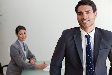 simsearch:400-05746962,k - Good looking businessman posing while his colleague is working in an office Stock Photo - Budget Royalty-Free & Subscription, Code: 400-05742793