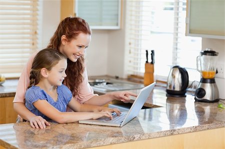 simsearch:400-05751173,k - Mother and daughter together with laptop behind the kitchen counter Stock Photo - Budget Royalty-Free & Subscription, Code: 400-05751174