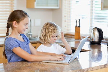 simsearch:400-05751173,k - Siblings together on the laptop in the kitchen Stock Photo - Budget Royalty-Free & Subscription, Code: 400-05751177