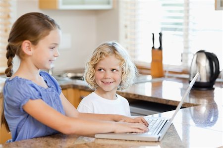 simsearch:400-05751173,k - Siblings together on the notebook in the kitchen Stock Photo - Budget Royalty-Free & Subscription, Code: 400-05751178