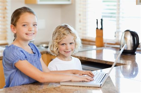 simsearch:400-05751173,k - Smiling siblings together on the laptop in the kitchen Stock Photo - Budget Royalty-Free & Subscription, Code: 400-05751179