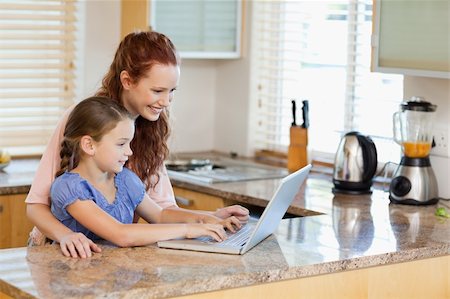 simsearch:400-05751173,k - Mother and daughter together with laptop in the kitchen Stock Photo - Budget Royalty-Free & Subscription, Code: 400-05751173