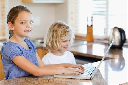 simsearch:400-05751173,k - Siblings together with laptop behind the kitchen counter Stock Photo - Budget Royalty-Free & Subscription, Code: 400-05751180