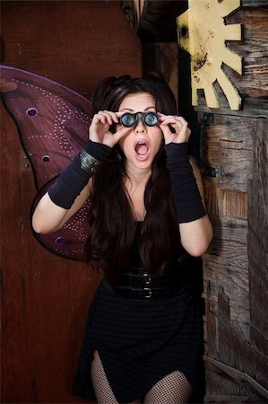 Surprised pretty fairy looks through loupe glasses in rustic location Stock Photo - Budget Royalty-Free & Subscription, Code: 400-05751344