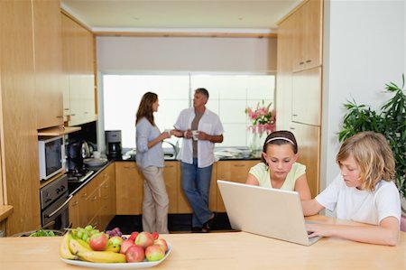 simsearch:400-05751173,k - Children with their laptop in the kitchen and parents behind them Stock Photo - Budget Royalty-Free & Subscription, Code: 400-05751698