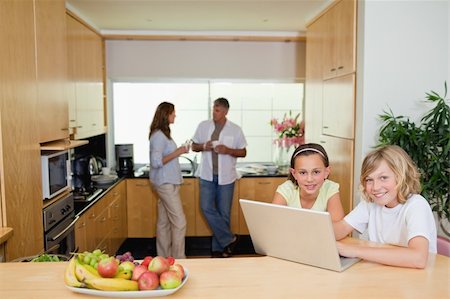simsearch:400-05751173,k - Children with their notebook in the kitchen and parents behind them Stock Photo - Budget Royalty-Free & Subscription, Code: 400-05751699