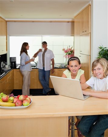 simsearch:400-05751173,k - Siblings with their laptop in the kitchen with parents behind them Stock Photo - Budget Royalty-Free & Subscription, Code: 400-05751700