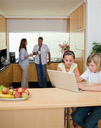 simsearch:400-05751173,k - Siblings with their notebook in the kitchen and parents behind them Stock Photo - Budget Royalty-Free & Subscription, Code: 400-05751701