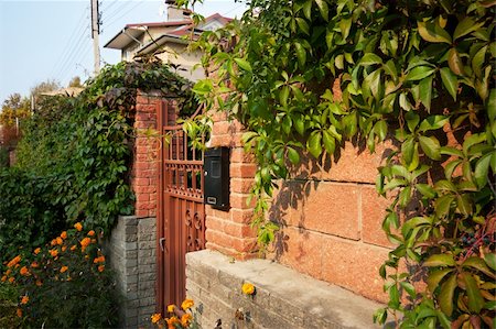 photo picket garden - Cottage garden gates with brick wall and lot of plants Stock Photo - Budget Royalty-Free & Subscription, Code: 400-05883342