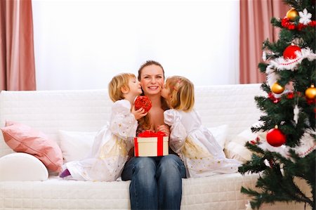 Two twins daughters presenting gift to mother and kissing her near Christmas tree Stock Photo - Budget Royalty-Free & Subscription, Code: 400-05883760