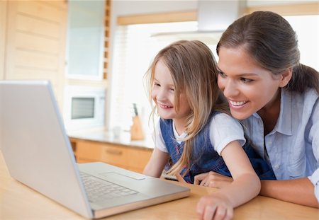 simsearch:400-05751173,k - Smiling mother and her daughter using a notebook in their kitchen Stock Photo - Budget Royalty-Free & Subscription, Code: 400-05894686