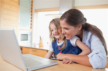 simsearch:400-05751173,k - Smiling mother and her daughter using a laptop in their kitchen Stock Photo - Budget Royalty-Free & Subscription, Code: 400-05894687