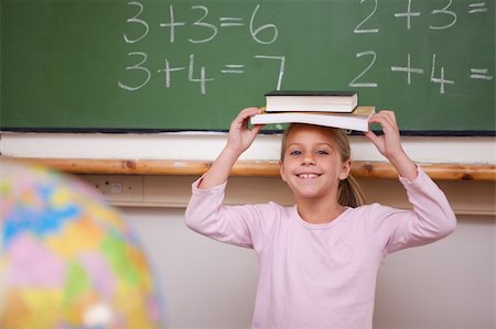 simsearch:400-05896424,k - Cute schoolgirl holding her book on her head in a classroom Stock Photo - Budget Royalty-Free & Subscription, Code: 400-05895078