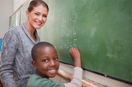 Smiling teacher and a pupil making an addition on a blackboard Stock Photo - Budget Royalty-Free & Subscription, Code: 400-05895180