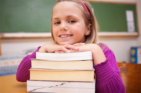 simsearch:400-05896424,k - Happy schoolgirl posing with a stack of books in a classroom Stock Photo - Budget Royalty-Free & Subscription, Code: 400-05895429