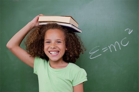 simsearch:400-05896424,k - Cheerful schoolgirl holding her book on her head in front of a blackboard Stock Photo - Budget Royalty-Free & Subscription, Code: 400-05896415