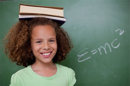 simsearch:400-05896424,k - Happy schoolgirl holding her book on her head in front of a blackboard Stock Photo - Budget Royalty-Free & Subscription, Code: 400-05896413