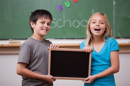 pupil in a empty classroom - Happy pupils holding a school slate in a classroom Stock Photo - Budget Royalty-Free & Subscription, Code: 400-05896518