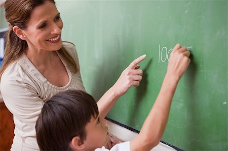 Schoolteacher helping a schoolboy doing an addition on a blackboard Stock Photo - Budget Royalty-Free & Subscription, Code: 400-05896552