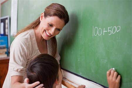 Smiling schoolteacher helping a schoolboy doing an addition on a blackboard Stock Photo - Budget Royalty-Free & Subscription, Code: 400-05896553