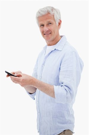 simsearch:400-06632132,k - Portrait of a man using his mobile phone while looking at the camera against a white background Stock Photo - Budget Royalty-Free & Subscription, Code: 400-05898529