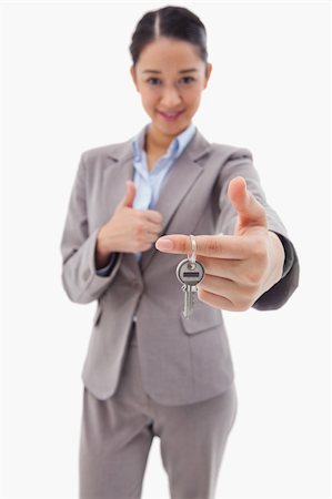 simsearch:400-04663994,k - Portrait of a businesswoman holding a key with the thumb up against a white background Stock Photo - Budget Royalty-Free & Subscription, Code: 400-05898622