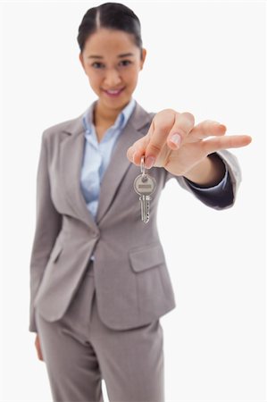 finger holding a key - Portrait of a smiling businesswoman holding a key against a white background Stock Photo - Budget Royalty-Free & Subscription, Code: 400-05898623
