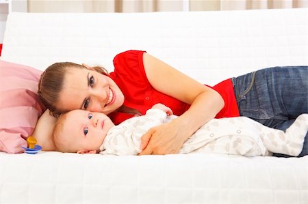 simsearch:400-05899085,k - Smiling mother with baby laying on couch Foto de stock - Super Valor sin royalties y Suscripción, Código: 400-05899072
