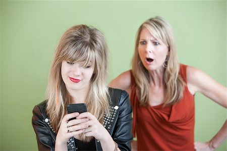 simsearch:400-05918419,k - Shocked mom watches teen use phone over green background Stock Photo - Budget Royalty-Free & Subscription, Code: 400-05904531