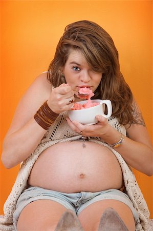 families eating ice cream - Hungry pregnant woman eats ice cream over orange background Stock Photo - Budget Royalty-Free & Subscription, Code: 400-05907901