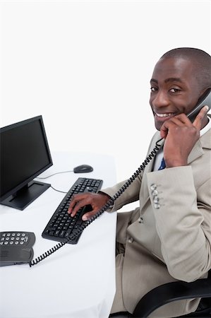 simsearch:859-06710917,k - Side view of a male secretary answering the phone while using a monitor against a white background Stock Photo - Budget Royalty-Free & Subscription, Code: 400-05900674