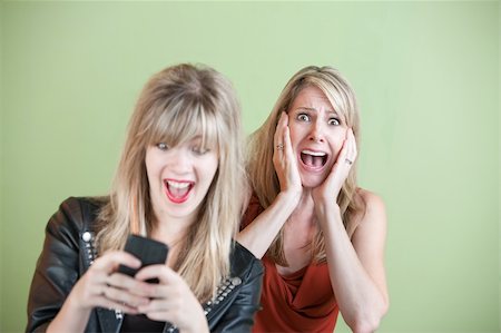 simsearch:400-05918419,k - Excited daughter texting with shocked mom behind her over green background Stock Photo - Budget Royalty-Free & Subscription, Code: 400-05918419