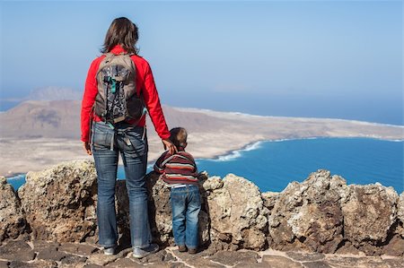 Back view young mother with backpack and son standing on cliff's edge and looking to a island. Stock Photo - Budget Royalty-Free & Subscription, Code: 400-05919648