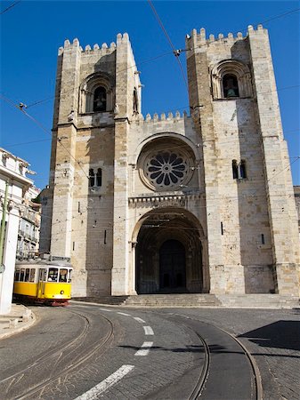 front of streetcar - Lisbon's ancient cathedral was built by Portugal's first king on the site of an old mosque in 1150 for the city's first bishop, the English crusader Gilbert of Hastings. With two bell towers and a rose window, the facade resembles a medieval fortress. Stock Photo - Budget Royalty-Free & Subscription, Code: 400-06065225