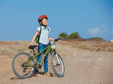 female vintage helmet - Happy teenager girl over a bicycle and looking the view, on a road Stock Photo - Budget Royalty-Free & Subscription, Code: 400-06065760