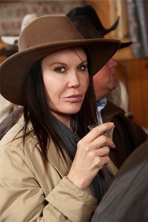 simsearch:400-06104096,k - A tough western woman looks at the camera before drinking her alcohol. Stock Photo - Budget Royalty-Free & Subscription, Code: 400-06060909