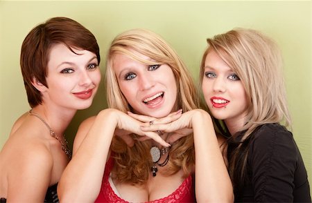 simsearch:400-04016564,k - Three attractive teen girls smile in front of a green wall for a portrait. Stock Photo - Budget Royalty-Free & Subscription, Code: 400-06060922