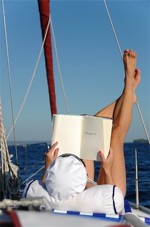 Young beautiful woman is relaxing and sunbathing while reading a book on a sailboat in the open adriatic sea. Book can be used as copy space for small alterations. Stock Photo - Budget Royalty-Free & Subscription, Code: 400-06074281