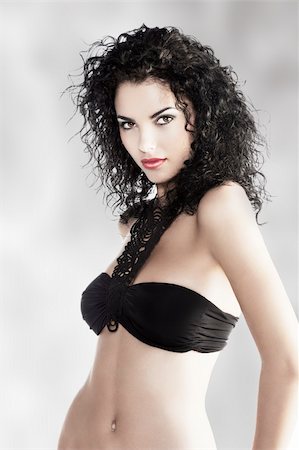 simsearch:400-05755679,k - young and very beautiful brunette with curly hair and deep red lips wearing a fashion black swimsuit and jewellery Stock Photo - Budget Royalty-Free & Subscription, Code: 400-06077651