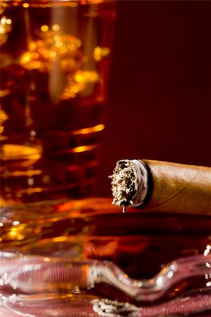 simsearch:400-05207678,k - Close-up selective focus of a burning cigar with a glass of whiskey in the background. Stock Photo - Budget Royalty-Free & Subscription, Code: 400-06079520
