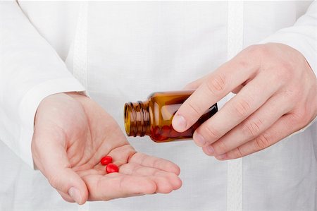 substance - Close-up photograph of a hand pouring red tablets out of a transparent bottle into another hand. Stock Photo - Budget Royalty-Free & Subscription, Code: 400-06086279